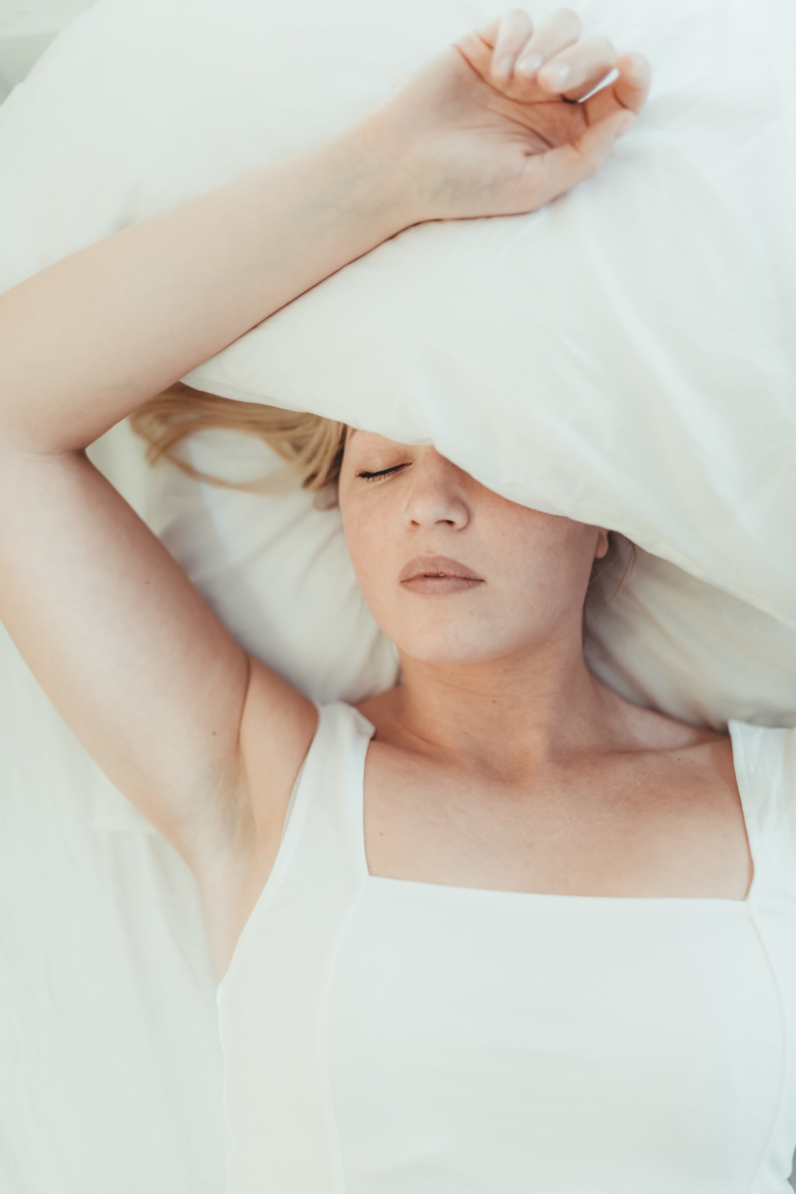 woman-lays-in-a-bed-with-a-pillow-over-her-head.jpg