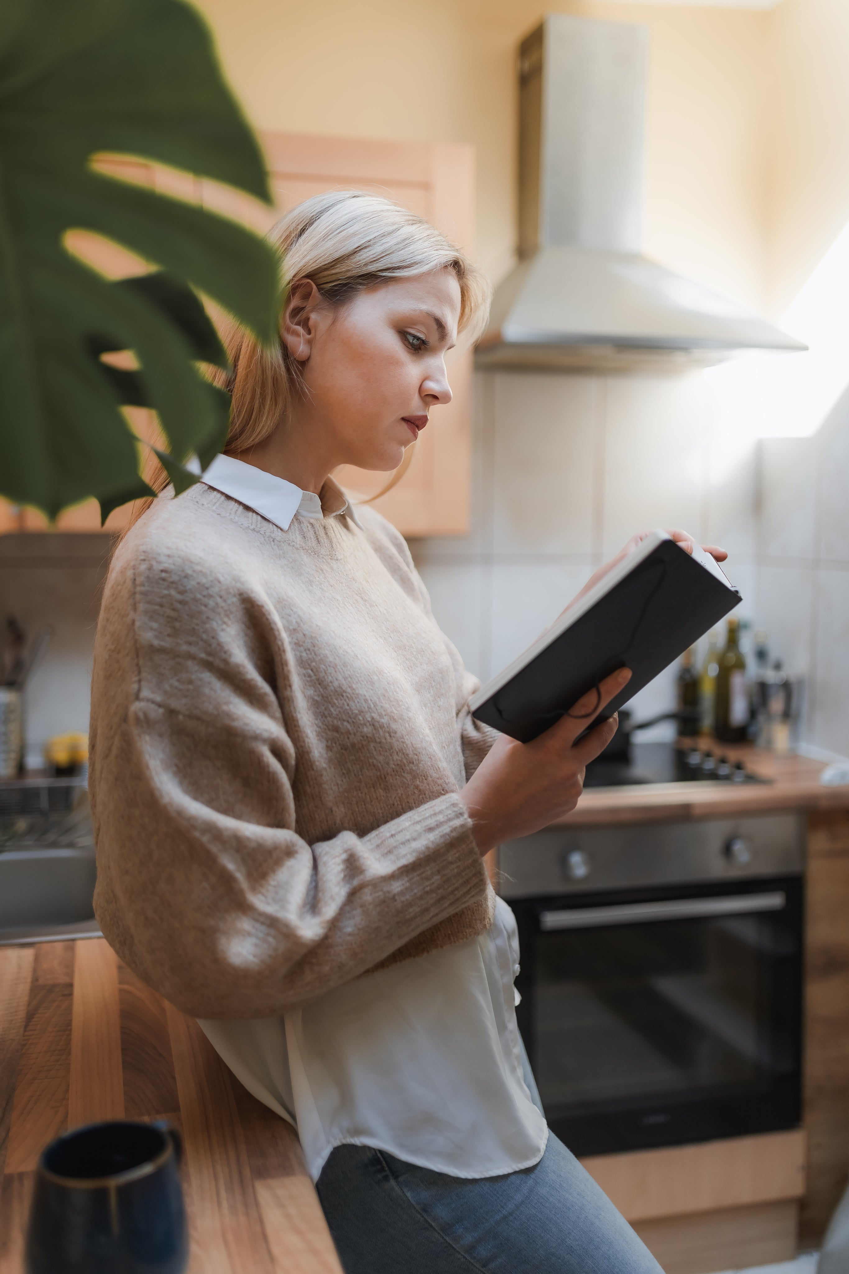 woman-stands-in-her-kitchen-reading-a-book.jpg